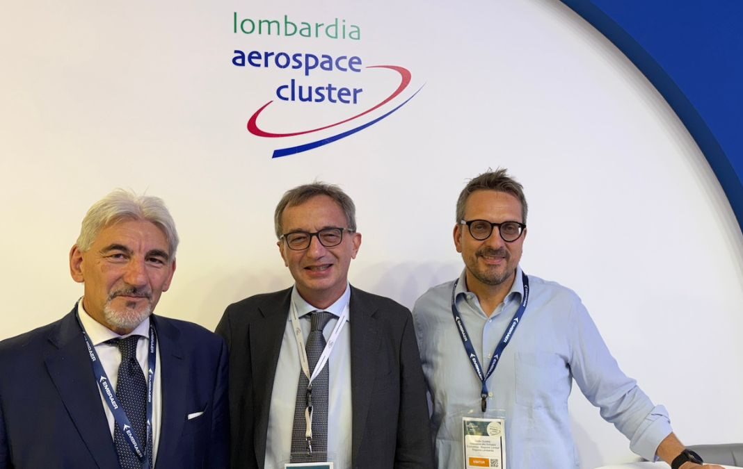 Raffaele Cattaneo, Paolo Cerabolini e Guido Guidesi allo stand del Lombardia Aerospace Cluster durante il Farnborough International Airshow 2026, in occasione della presentazione dei dati sull'export aerospaziale lombardo.