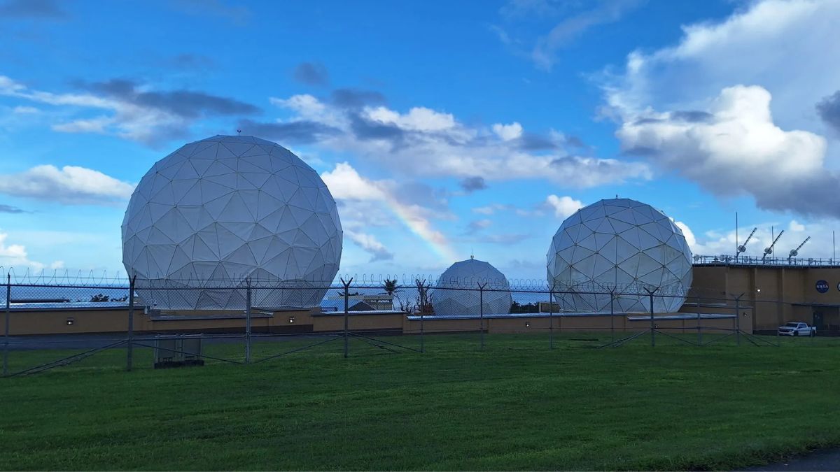 Antenne della stazione NASA di Guam protette dai radome, con un arcobaleno sullo sfondo