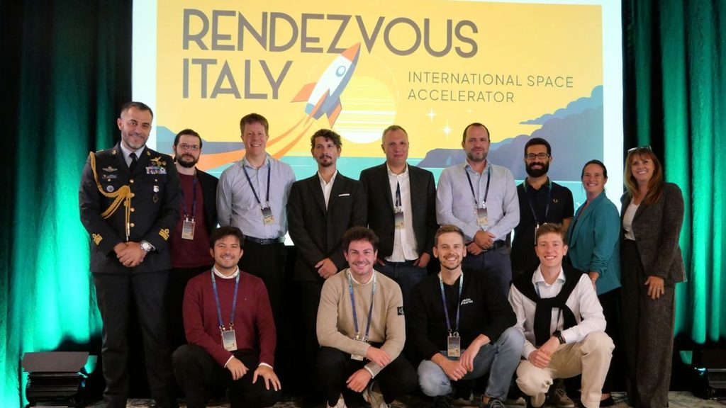 DTA, concluso Rendezvous Italy in New Mexico: CUS-GNC vince la Pitch Competition 1 Foto di gruppo all'evento Rendezvous Italy, programma in cui CUS-GNC ha vinto la Pitch Competition, davanti allo schermo con il logo dell'iniziativa.